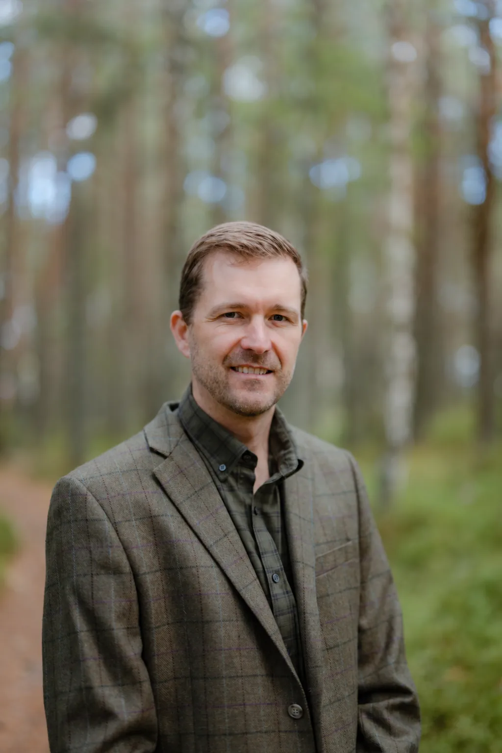 Nat Baldwin in a tweed jacket in a Highland pine forest